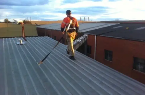 Roofer working safely on an industrial roof